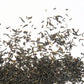 Dried Assam Banaspaty black tea leaves spread out on the table in close-up.